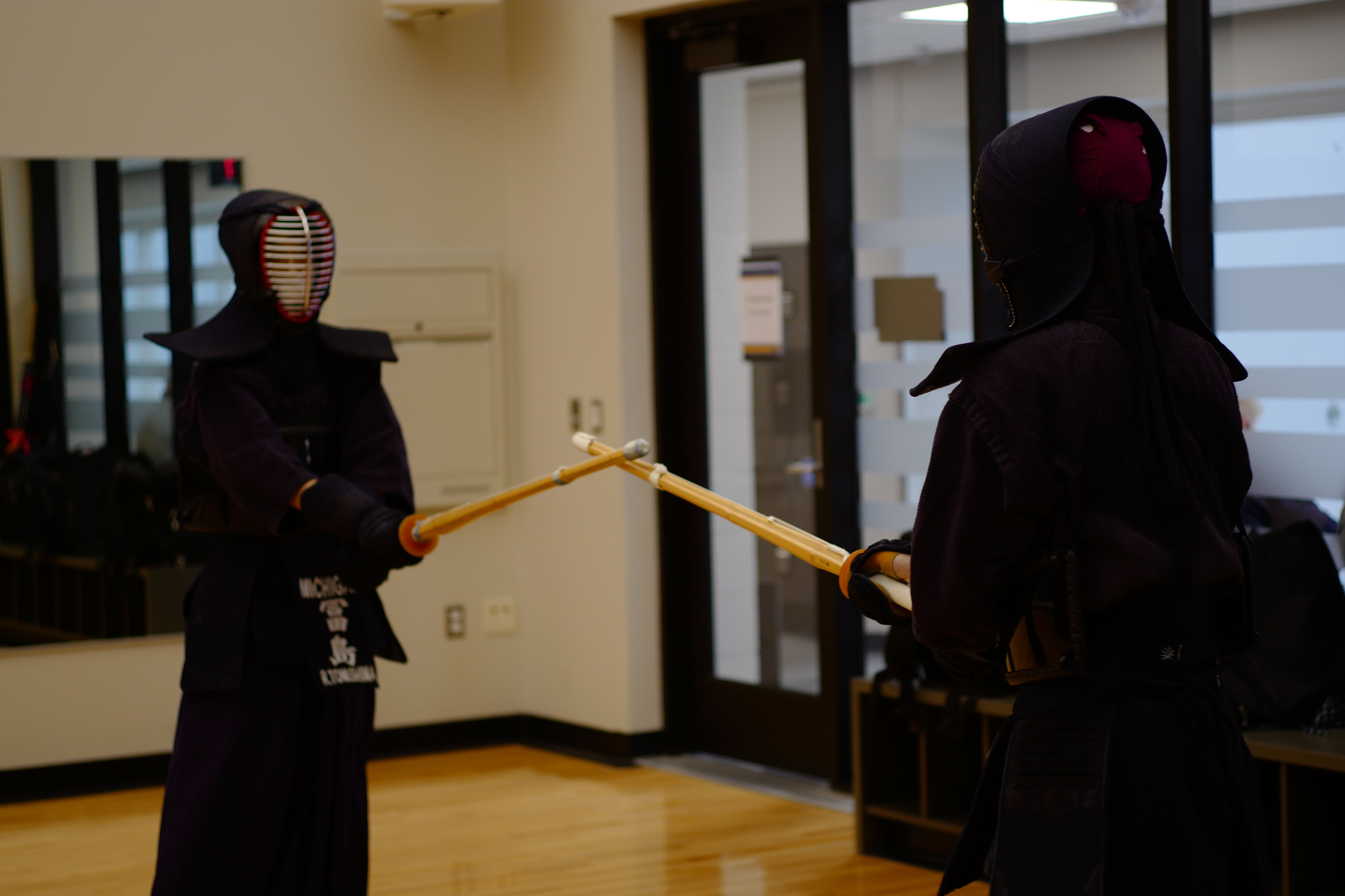 Two club members in kendo armor holding bamboo practice swords, facing each other in the ready position.